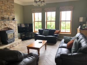a living room with leather couches and a fireplace at Country house in Killyhevlin
