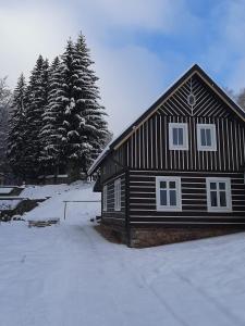 une maison noire et blanche dans la neige dans l'établissement Chata Sára, à Janské Lázně