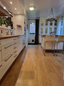 cocina con armarios blancos y suelo de madera en Riverside villa en Borlänge