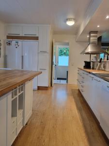 a kitchen with white cabinets and a wooden floor at Riverside villa in Borlänge