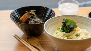 two bowls of food on a wooden table with chopsticks at TOKIO's HOTEL in Tokyo