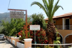 a palm tree and a sign in front of a building at Lido Sofia Apartments in Agios Gordios