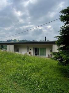 a white house with a grassy field in front of it at Sunhand home in Eibiswald