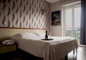 una camera con un letto, una bottiglia e un bicchiere di vino di Hotel Frejus a Collegno