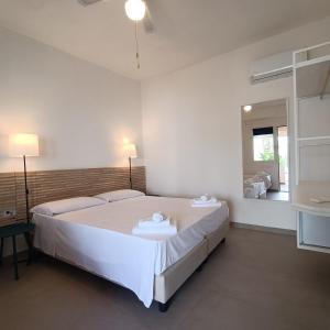 a bedroom with a large white bed and a mirror at Lido Di Alghero Rooms on the Beach in Alghero