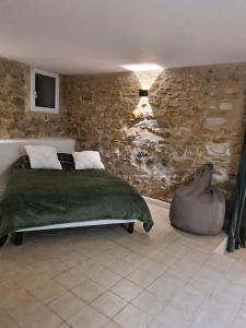 1 dormitorio con cama y pared de piedra en La maison du bonheur, en Caumont-sur-Durance