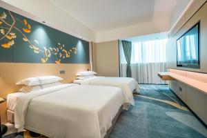 a hotel room with two beds and a flat screen tv at Wiffton Hotel -Former Tokai Hotel - Xiaobei Metro Station - Free shuttle bus during Canton Fair in Guangzhou