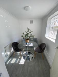 格雷夫森德的住宿－Gravesend 1 Bedroom Apartment 2 Min Walk to Station - longer stays available，一张带两把椅子的玻璃桌和盆栽植物