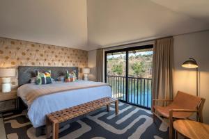 a bedroom with a large bed and a balcony at Riverhorse Lodge in Lanseria