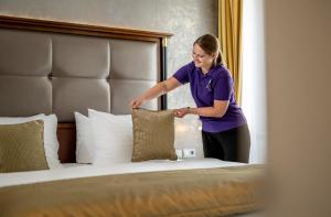 a woman putting a pillow on a bed at IMLAUER HOTEL PITTER Salzburg in Salzburg