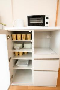 a white kitchen cabinet with a microwave and plates at Villa Futaba若松町 in Hakodate