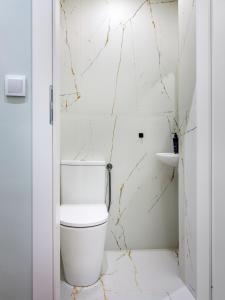 a white bathroom with a toilet and a sink at Tyzenhauz Apartments Pawia Street in Krakow