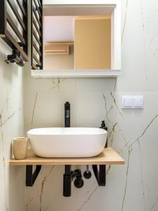 a bathroom with a white sink on a wooden shelf at Tyzenhauz Apartments Pawia Street in Krakow