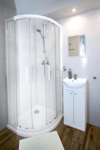 a white bathroom with a shower and a sink at Apartament przy Zdrojowej in Ciechocinek