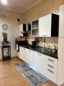 a kitchen with white cabinets and a black counter top at Matilda’s Apartment in Strambino