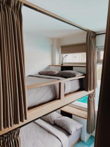 two bunk beds in a room with curtains at Kos One Hostel in Canggu