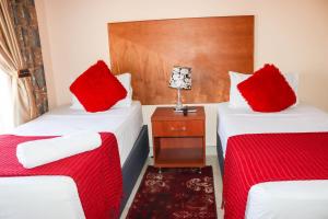 2 Betten in einem Zimmer mit roten Kissen darauf in der Unterkunft Meet Mekaar Resorts - Nquthu Hotel in Nqutu