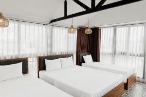 2 camas en una habitación con ventanas en Tabalo Hostel Hanoi, en Hanói