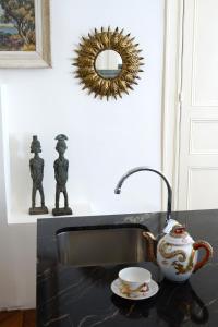 eine Spüle mit einem Wasserkocher und einem Spiegel in der Unterkunft Maison Eugénie in Luchon