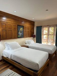 two beds in a bedroom with wood paneling at บ้านยุ้งฮีลล์รีสอร์ท Baan Yung Hill Resort in Ban Pa Sang