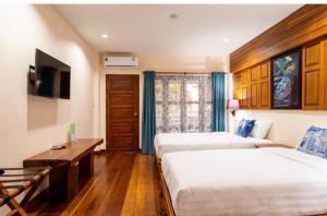 Ban Pa Sangにあるบ้านยุ้งฮีลล์รีสอร์ท Baan Yung Hill Resortのベッド2台とテレビが備わるホテルルームです。