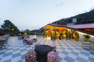 a patio with tables and chairs on a checkered floor at The Rose, Kasauli -A Four Star Lavish & Luxury Hotel in Kasauli