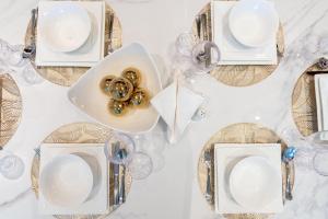 a white table with plates and glasses on it at Ultimate Stay Port de La Mer with Burj Khalifa Views from the Bed next to the Beach in Dubai