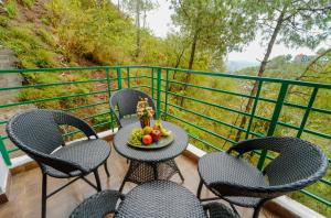 a balcony with chairs and a table with a bowl of fruit at The Rose, Kasauli -A Four Star Lavish & Luxury Hotel in Kasauli