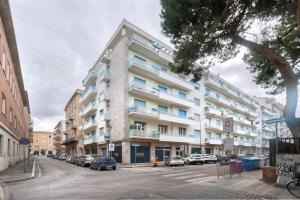 un gran edificio blanco con coches estacionados frente a él en Blue Horizon, en Pescara