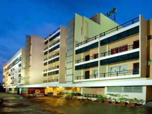 a large white building with plants in a parking lot at Hotel Subam in Palni