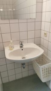 um lavatório branco numa casa de banho com azulejos brancos em Einzelbettzimmer in Ramstein em Ramstein-Miesenbach
