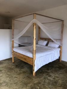 1 dormitorio con cama de madera y dosel en Jua Manyara Lodge & Camp Site, en Mto wa Mbu