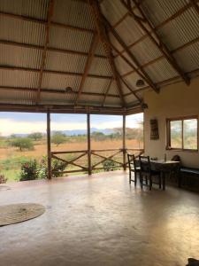 a room with a table and chairs and a view of a field at Jua Manyara Lodge & Camp Site in Mto wa Mbu