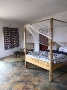 1 dormitorio con cama de madera y dosel en Jua Manyara Lodge & Camp Site en Mto wa Mbu