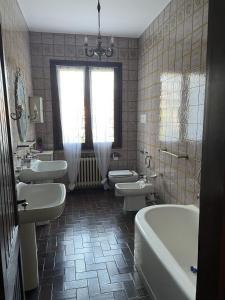 a bathroom with three sinks and a tub and toilets at Villa Giacinti in Padova