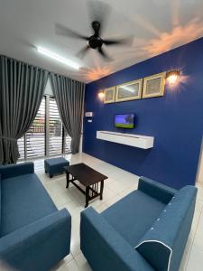 a living room with two blue couches and a ceiling fan at Arifz Zai Homestay in Batu Kurau