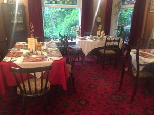 a dining room with two tables and chairs and a window at Oakfield Lodge Guest House Stockport in Marple