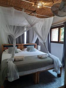 a bedroom with a bed with a canopy at Dhow Blue * Tofo Beach in Praia do Tofo