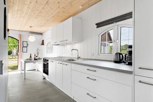 una cucina bianca con armadi bianchi e una finestra di First Camp Hasmark Camping Resort & Cottages a Otterup Altre 19 foto