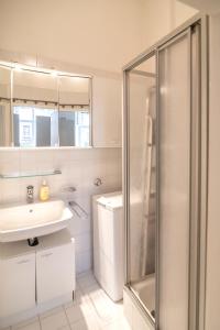 een witte badkamer met een douche en een wastafel bij Cozy Central Flat Spittelberg in Wenen