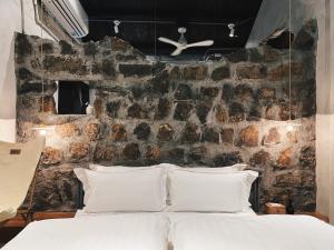 een slaapkamer met een stenen muur en een bed met witte kussens bij 嶼民宿 Yu Apartment in Jiufen