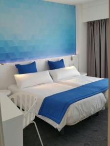 ein Schlafzimmer mit einem großen Bett mit blauen und weißen Kissen in der Unterkunft Estudiotel Alicante in Alicante