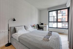 a white bedroom with a bed and a window at Apartments Doki by TriApart in Gdańsk