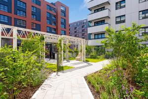a garden with a pergola in front of buildings at Apartments Doki by TriApart in Gdańsk