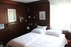 1 dormitorio con 1 cama grande con sábanas blancas y ventana en Ferienwohnung Stölben en Daun