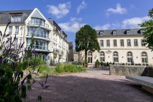 un grand bâtiment blanc avec un arbre en face dans l'établissement Villa Lara Hotel, à Bayeux
