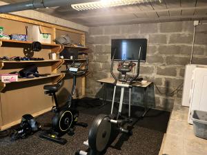 a room with a desk with a television and weights at Charming house near the sea in Courseulles-sur-Mer