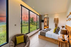 a bedroom with large windows and a bed and a chair at Brand NEW 6BR Villa Amazing VIEWS in Ubud