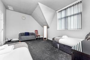1 dormitorio con 2 camas, silla y ventana en Hazel Dene - Charming 5 Bedroom, 1 Bath Home in Nottingham! en Nottingham