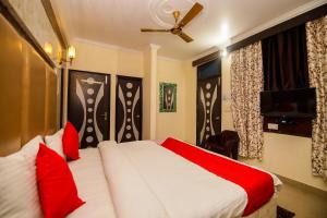 Bajaura的住宿－OYO 10154 47 Hill，配有红色枕头的床的酒店客房